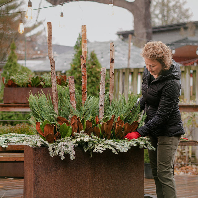 seasonal winter arrangement with woman standing by it
